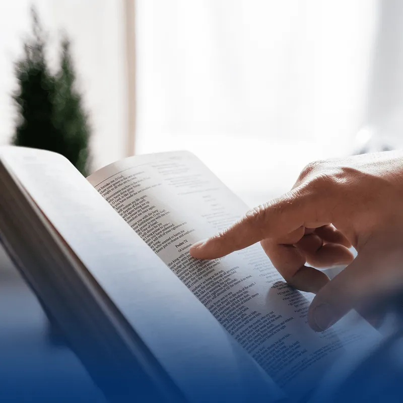Mão acompanhando a leitura da Bíblia